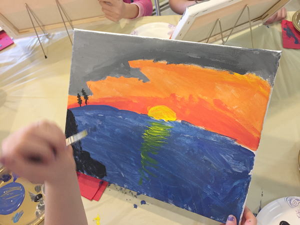 child painting the sunset over water